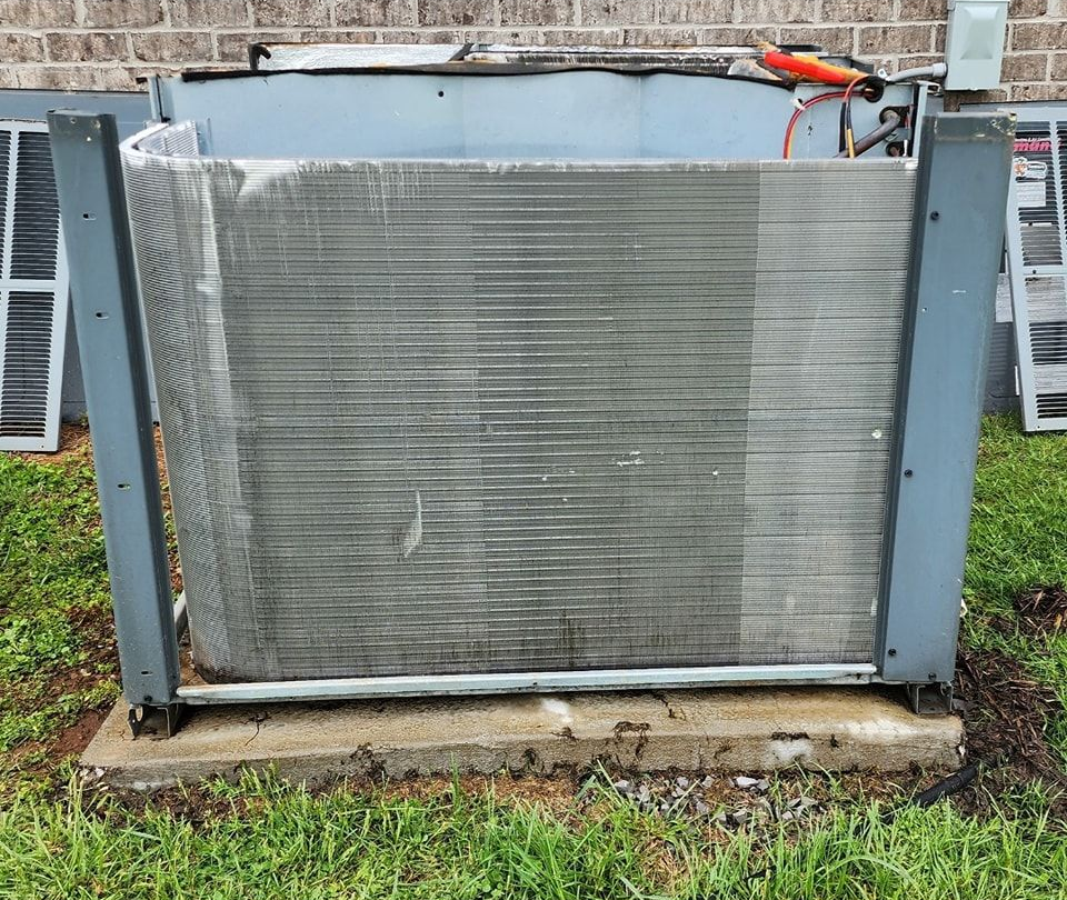 Gray metal industrial panel or gate outdoors on a concrete base with grass around it.