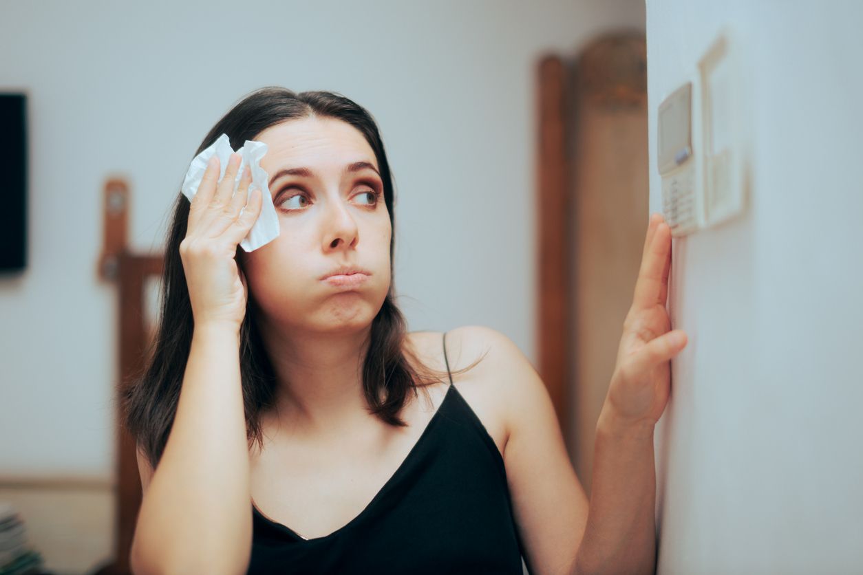 A woman is wiping her face with a napkin while looking at herself in the mirror.