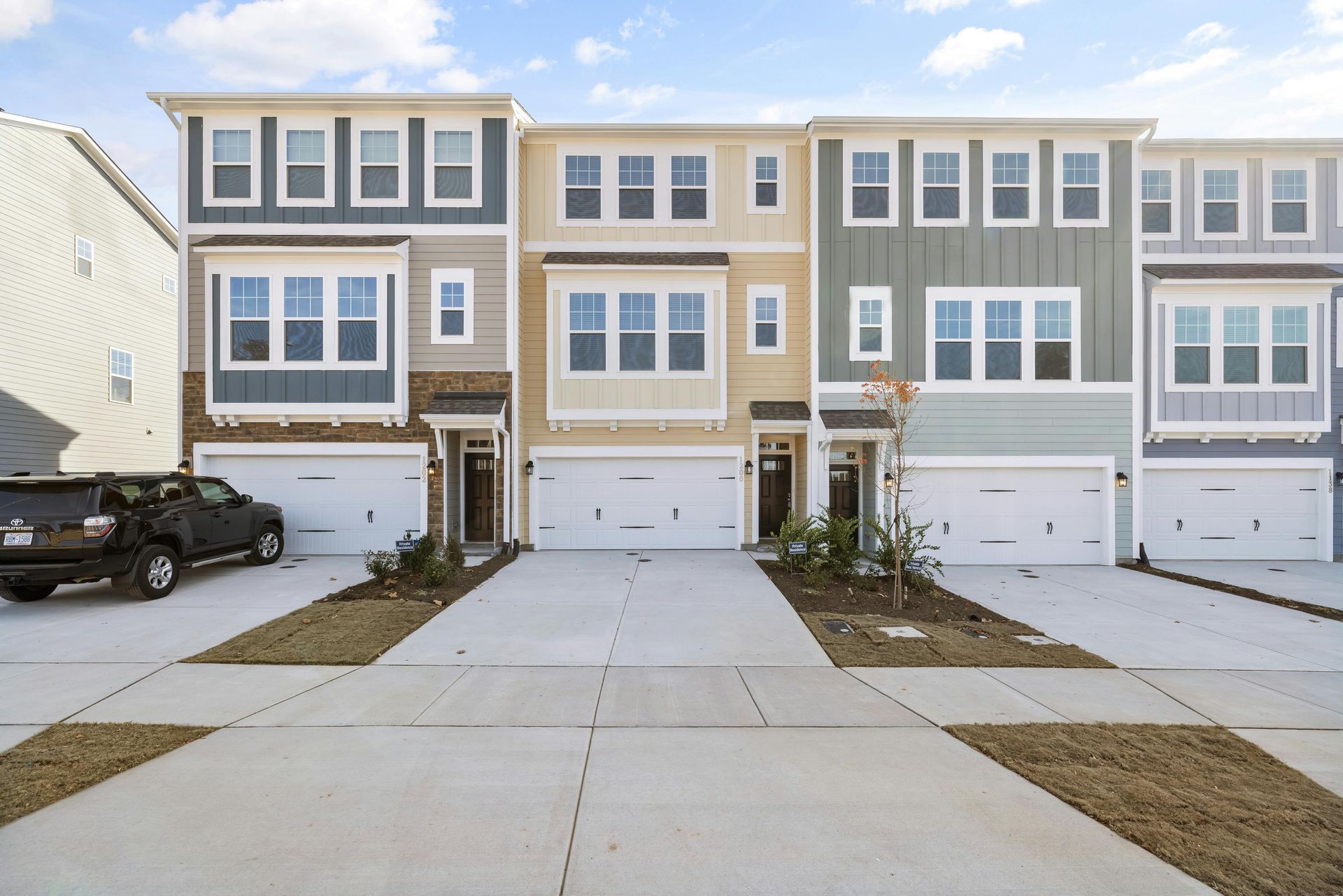 A row of houses with cars parked in front of them