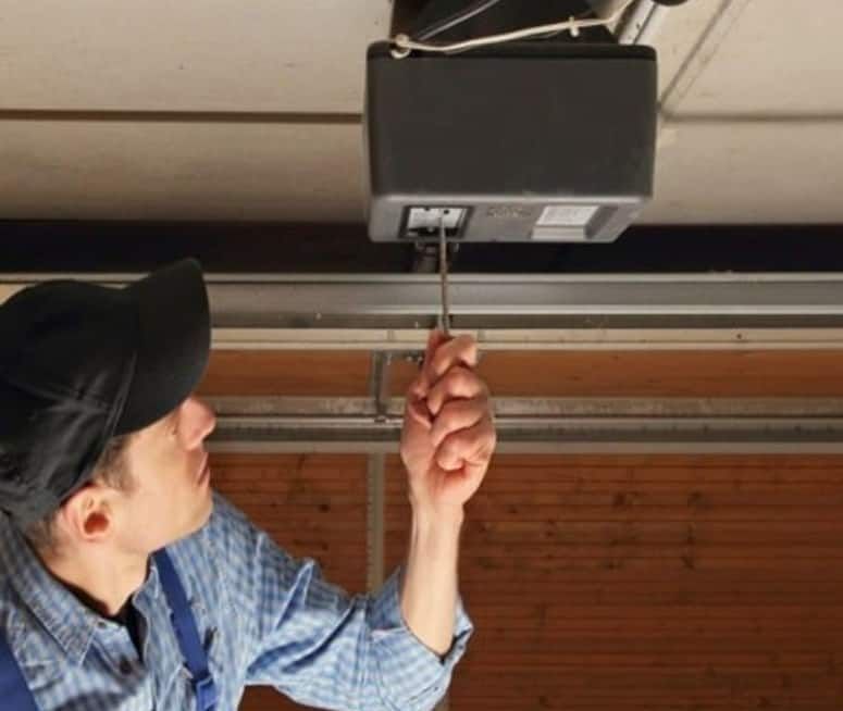 A man is fixing a garage door with a screwdriver.