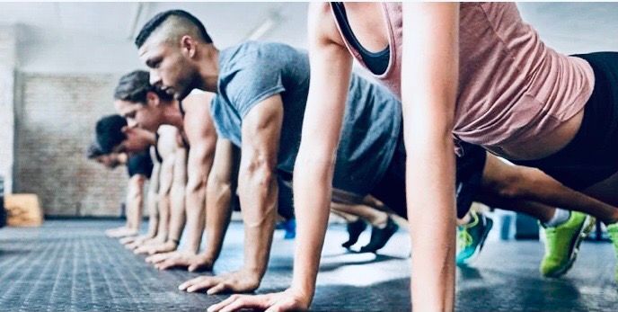 A group of people are doing push ups in a gym.