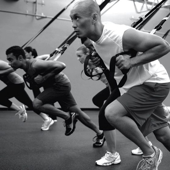 A man and a woman are holding ropes in a gym.