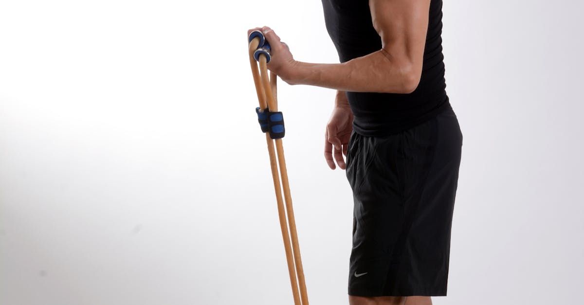 A man in a black tank top and black shorts is holding an endurance band.