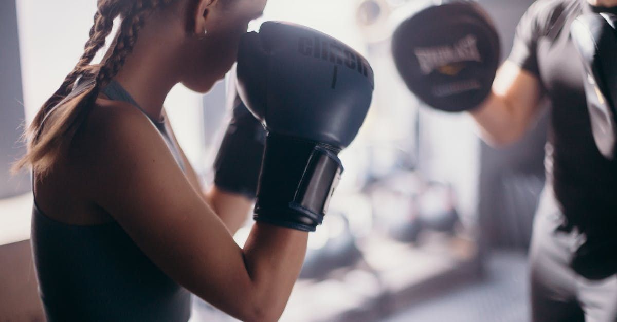 A woman is boxing with a man in a gym.