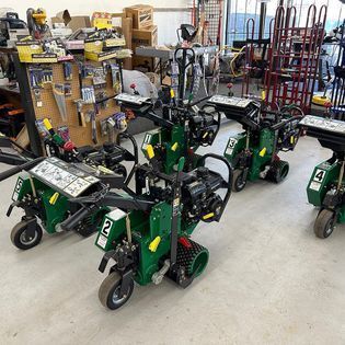 A bunch of green vehicles are parked in a room.