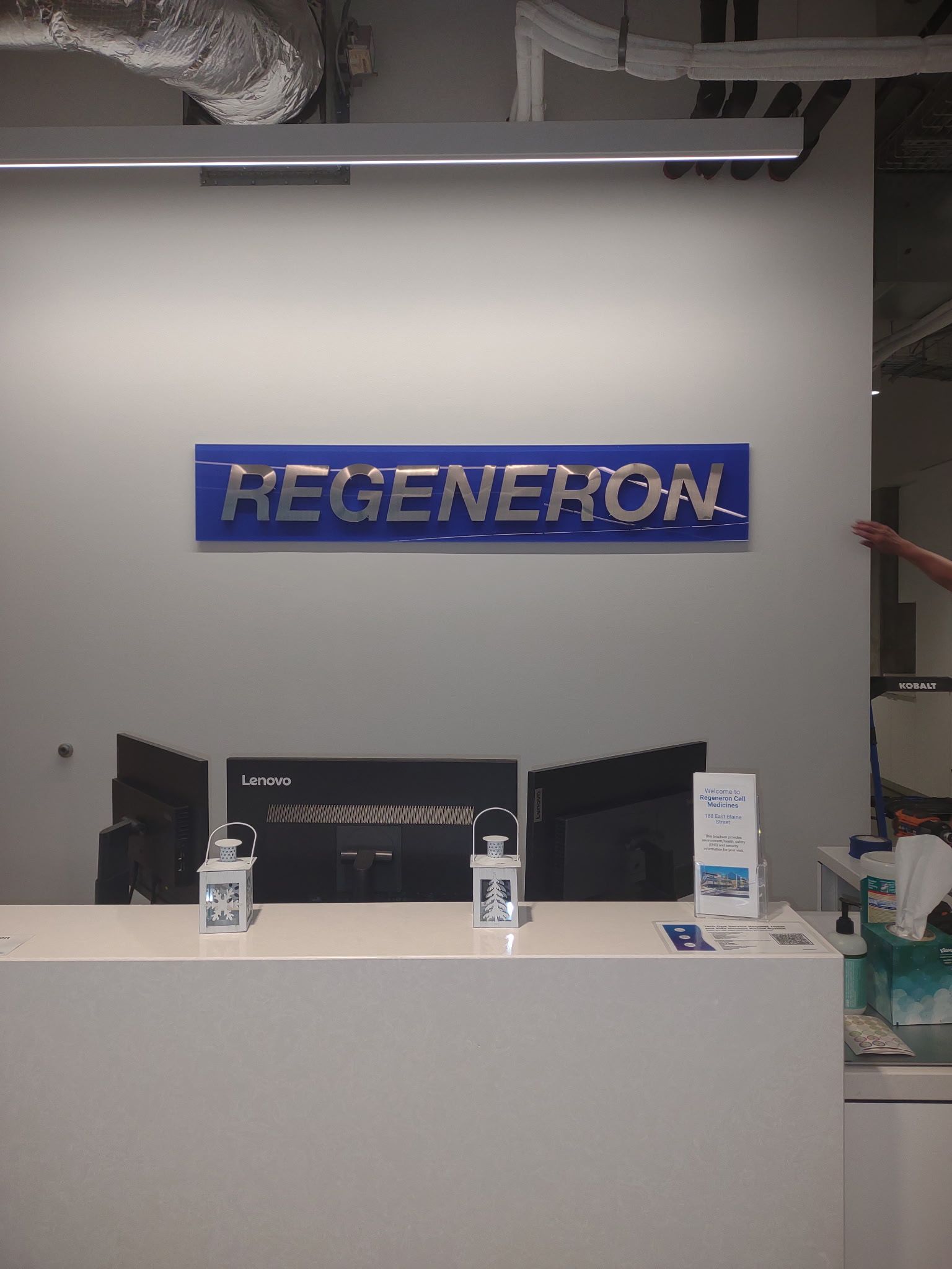 Regeneron reception desk with blue sign and monitors in a modern office lobby