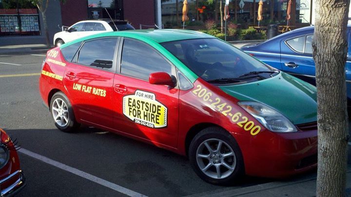 A red and green taxi parked on a street with