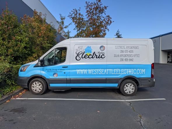 A West Seattle Electric work van parked in a lot, featuring white and blue branding with contact and website information.