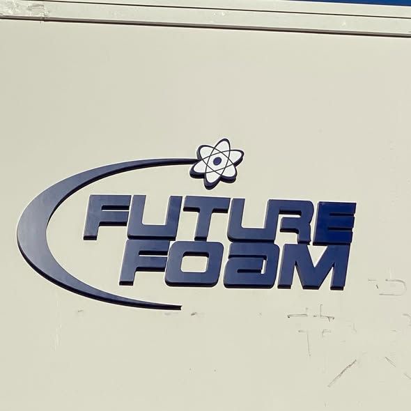 A blue, 3D logo on a light wall that reads