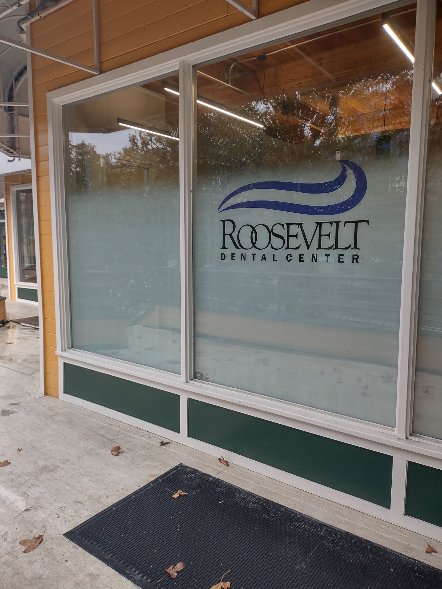 Glass storefront with Roosevelt Dental Center logo and name above a black entrance mat