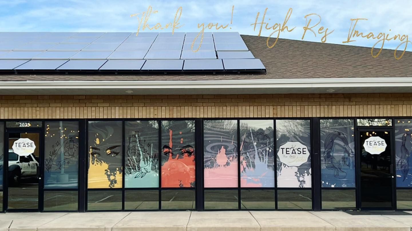 Exterior of a commercial building with solar panels on the roof and colorful abstract window decals featuring