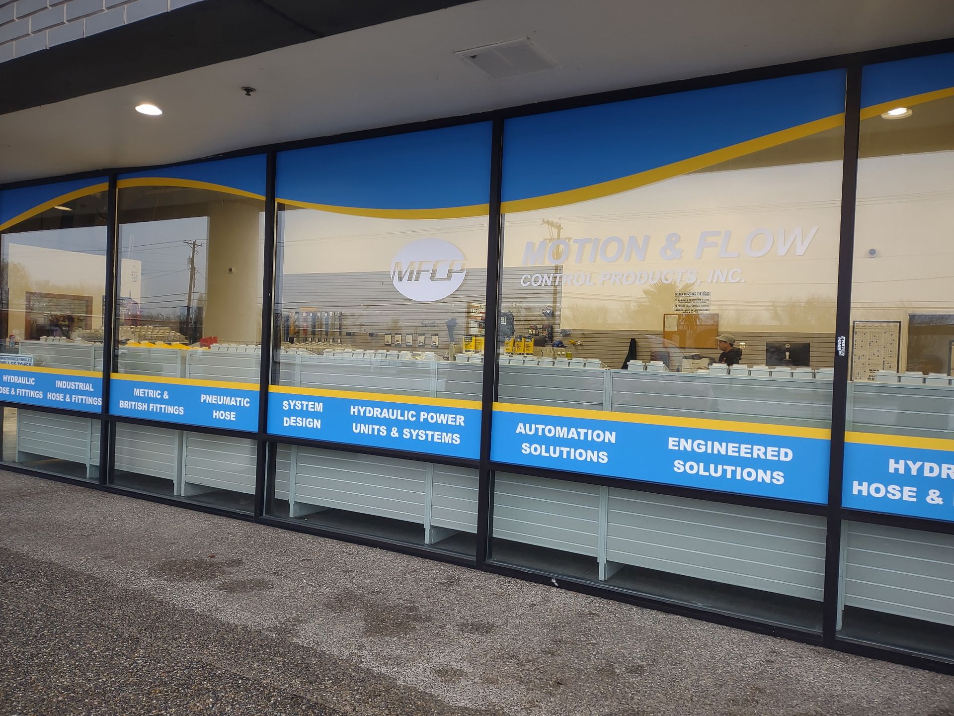 A storefront with a blue and yellow sign listing industrial services like automation, hydraulic power, and engine solutions.