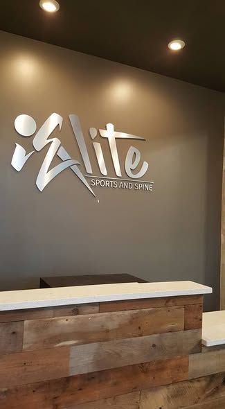 Reception desk with a rustic wood front and white counter against a dark gray wall featuring a silver