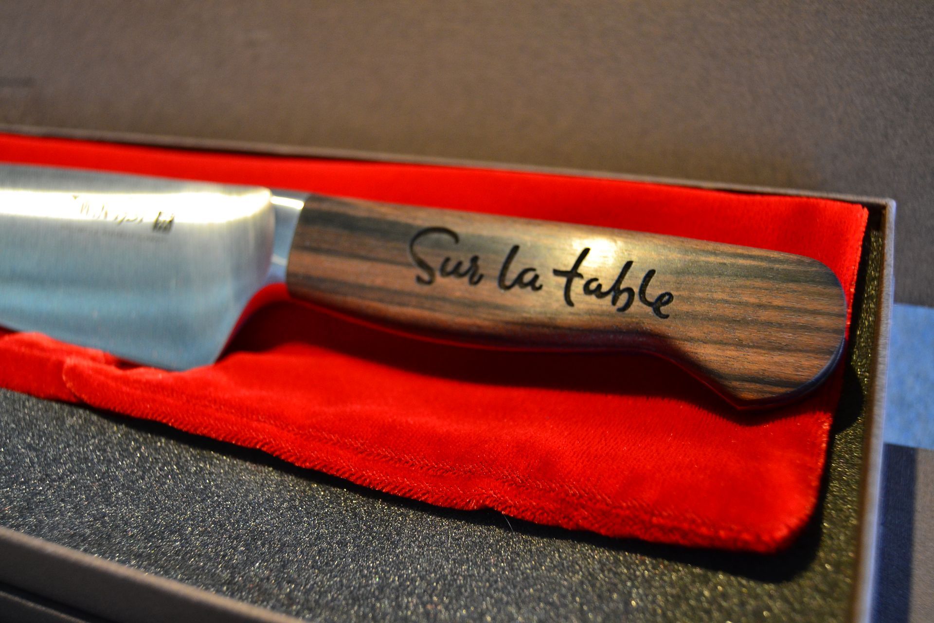 A kitchen knife with a wood-grain handle engraved with 