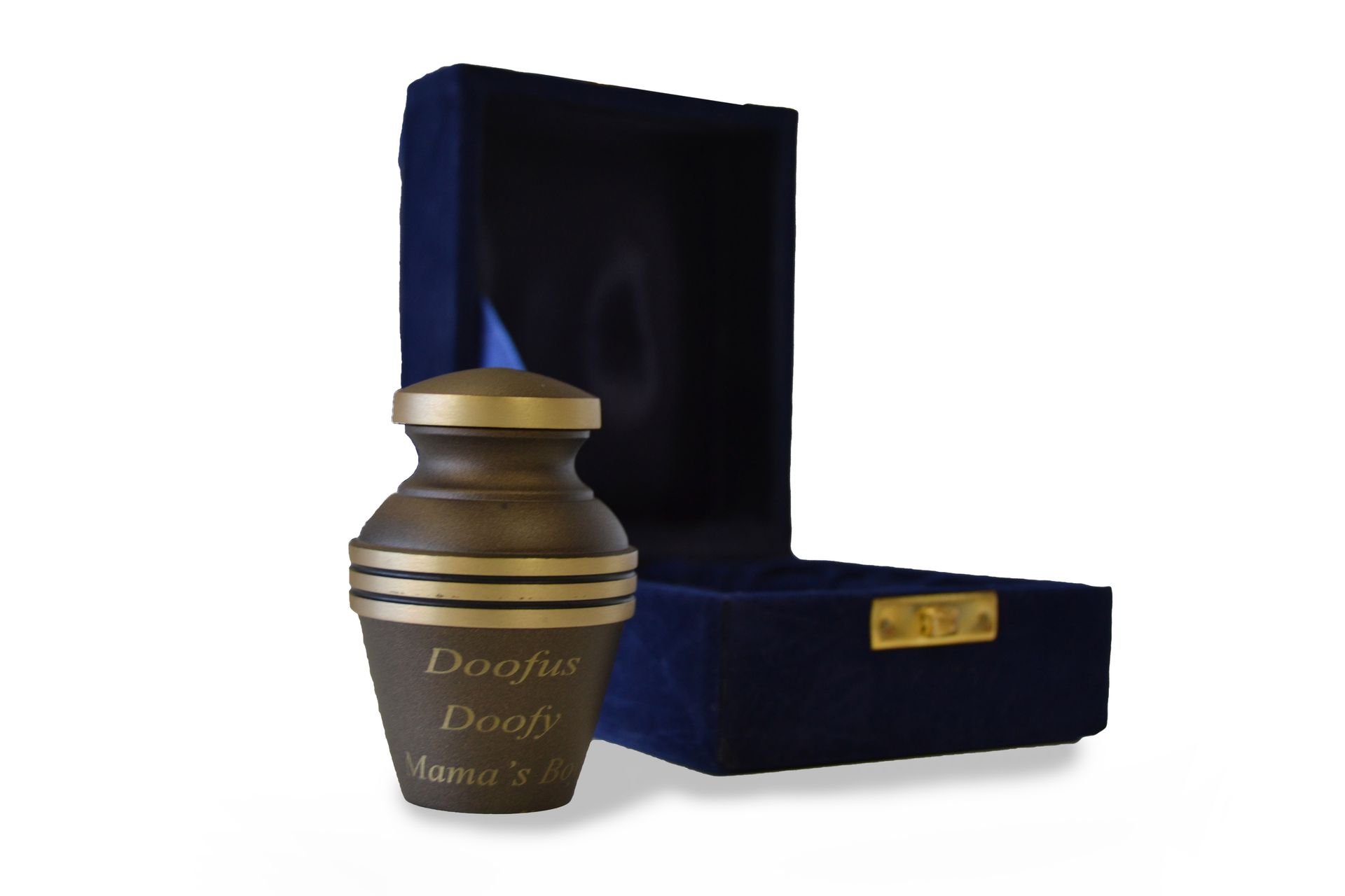A small, dark metal urn with gold bands sits beside an open, velvet-lined navy blue presentation box.