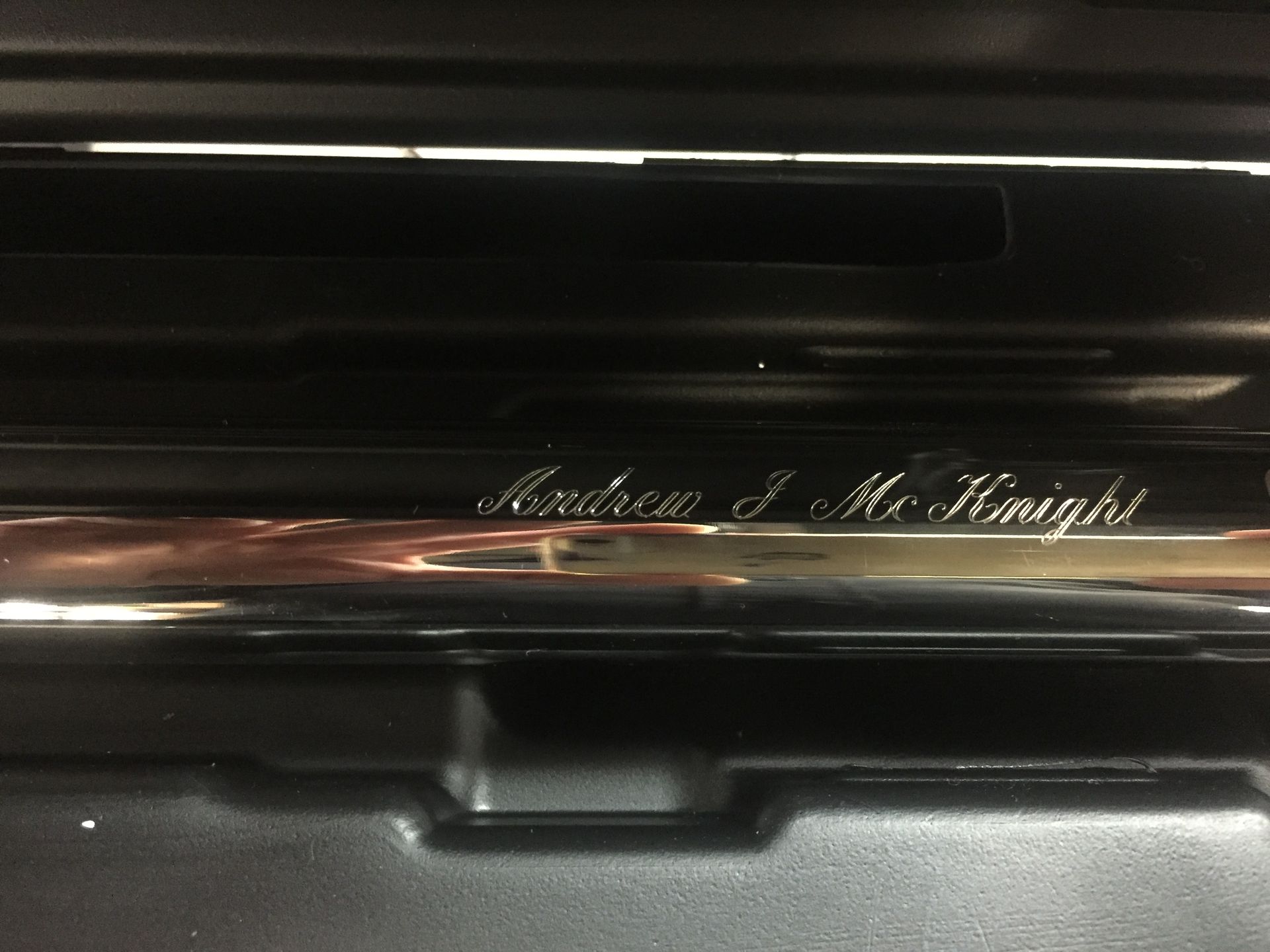 A polished metal surface inside a dark case with the name 