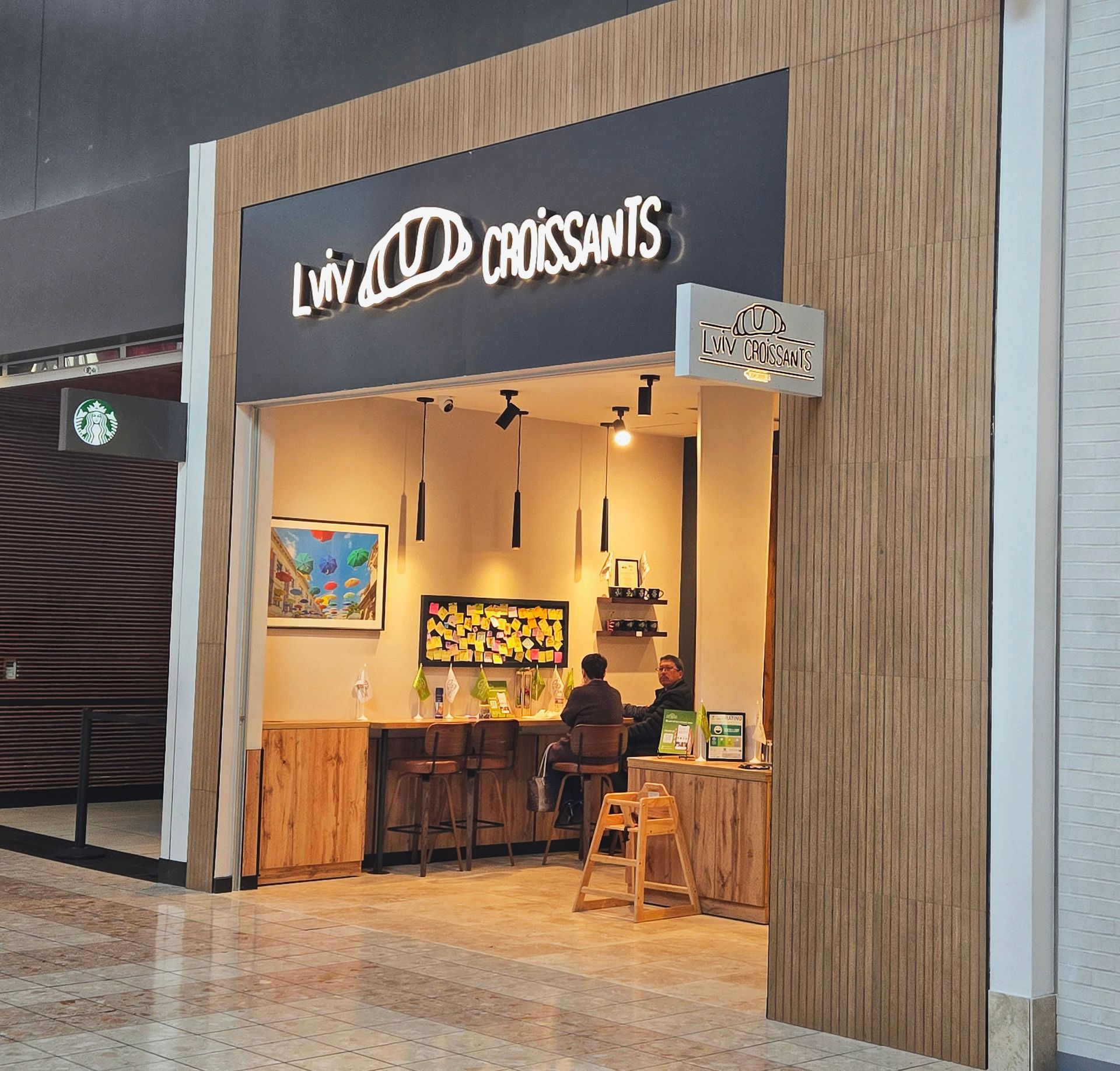 A Lviv Croissants bakery kiosk inside a shopping center, with wooden accents and indoor seating.