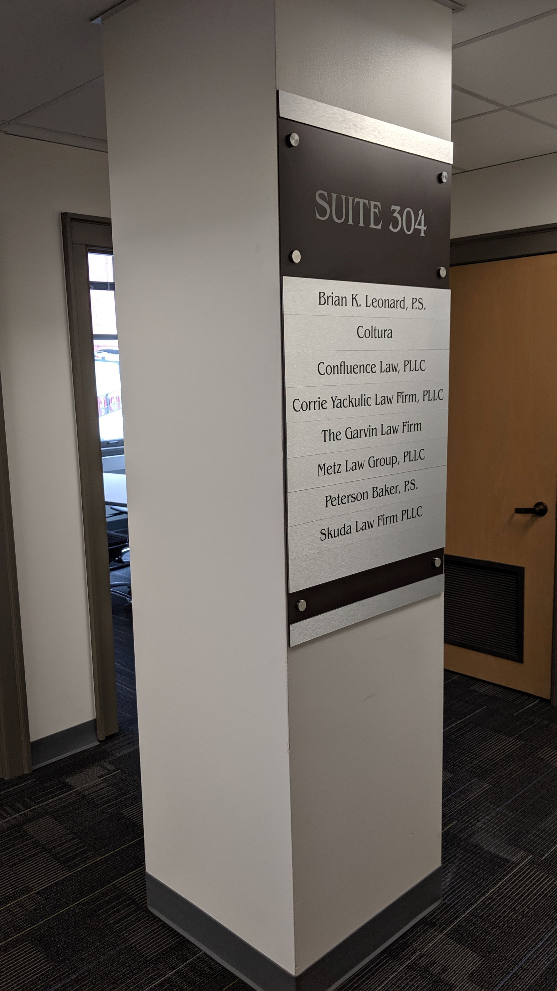 A white pillar in an office hallway displays a sign labeled