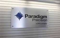 A metal sign on a white wall reads