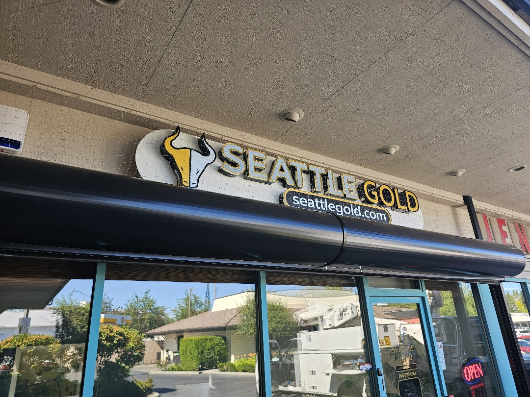 Storefront sign for Seattle Gold featuring a split yellow and white bull logo above the business name.