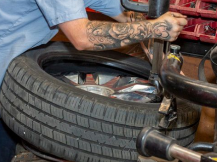 Mechanic using a machine to remove a tire from a wheel in a garage