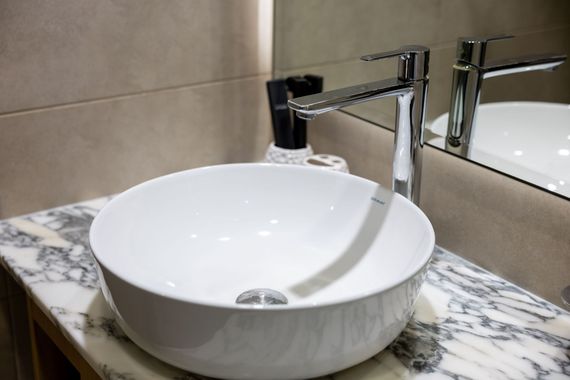 Modern bathroom sink with white bowl basin, chrome faucet, and marble countertop