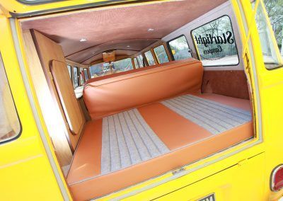 Yellow van interior with orange and gray bench seating and windows lined with curtains