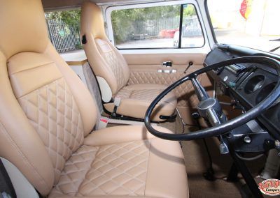 Beige car interior with quilted seats and a steering wheel.