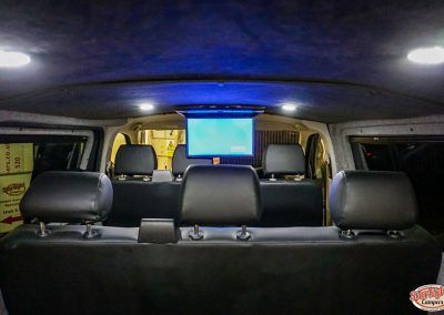 Back seat view of a car interior at night, with a screen mounted near the front seats.