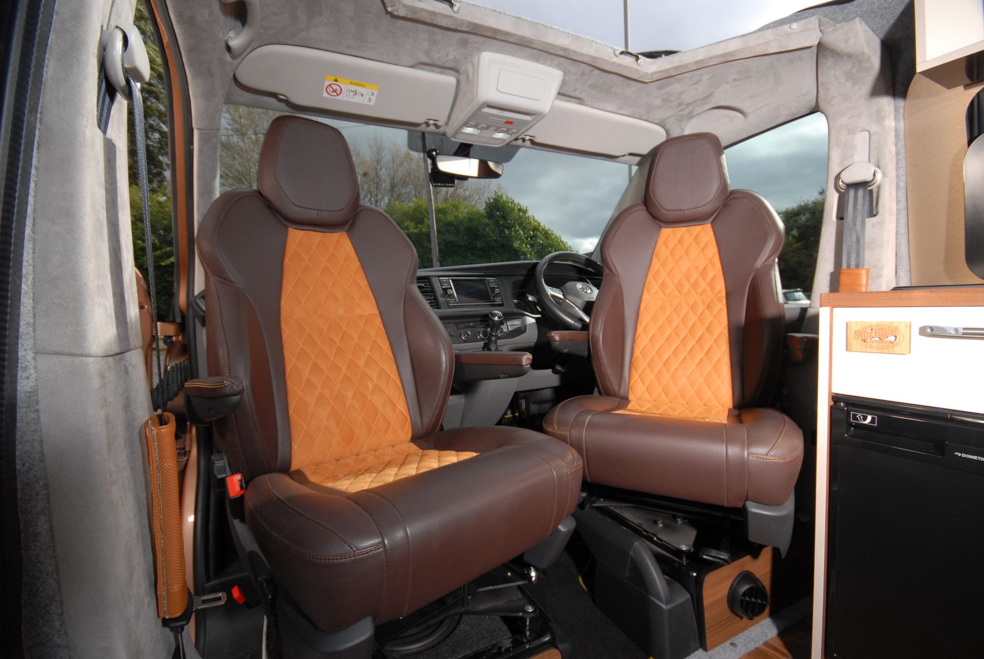 Front cabin of a vehicle with two brown and orange seats and a view through the windshield