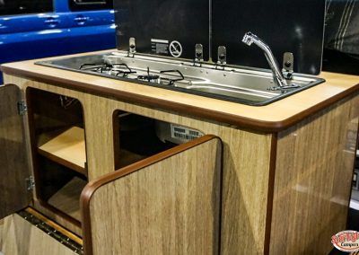 Built-in stainless steel sink and faucet in a wood-paneled camper kitchenette
