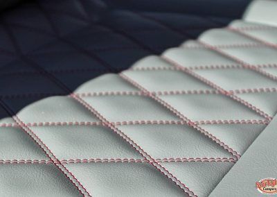 Close-up of a quilted gray leather car seat with red stitching