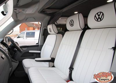 White VW van interior with custom white leather seats and embroidered VW headrests
