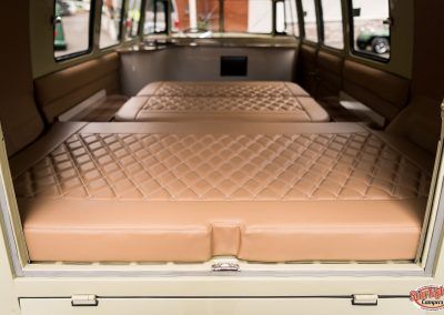 Tan leather bench seats inside a vehicle, viewed from the open rear hatch