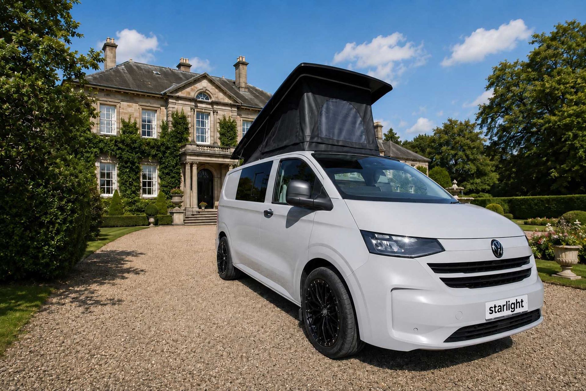 White cargo van parked on a gravel drive in front of a large stone house under a sunny sky