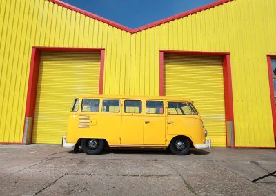 Yellow van parked outside yellow warehouse with red trim and closed garage doors
