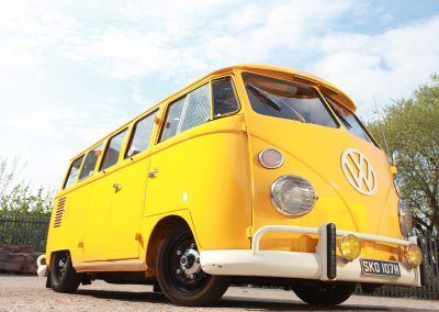 Yellow vintage Volkswagen van parked outdoors under a blue sky.