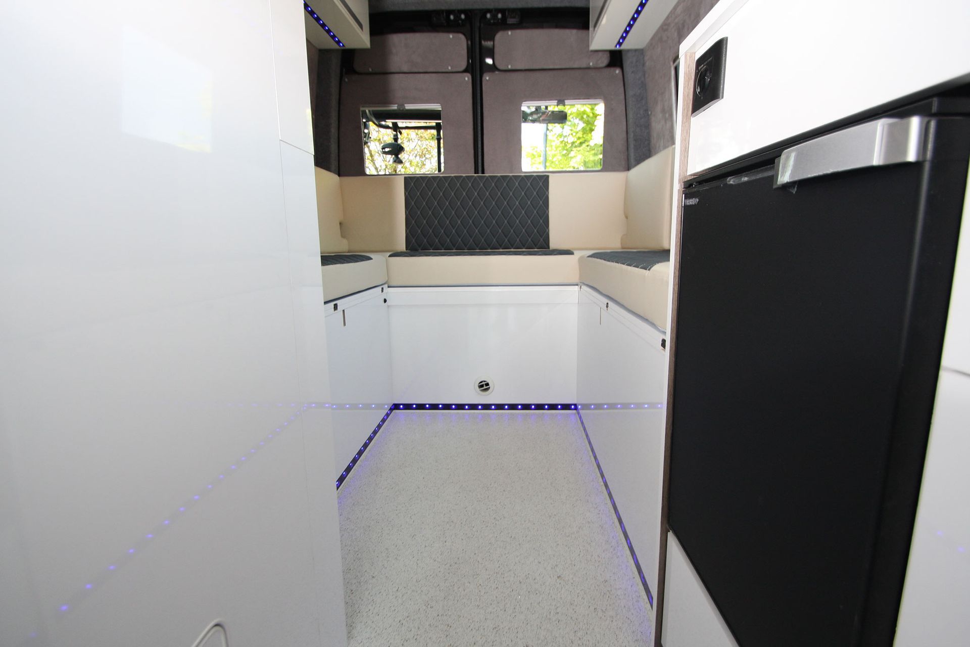 Narrow modern kitchen interior with white walls, black cabinets, and a small window.