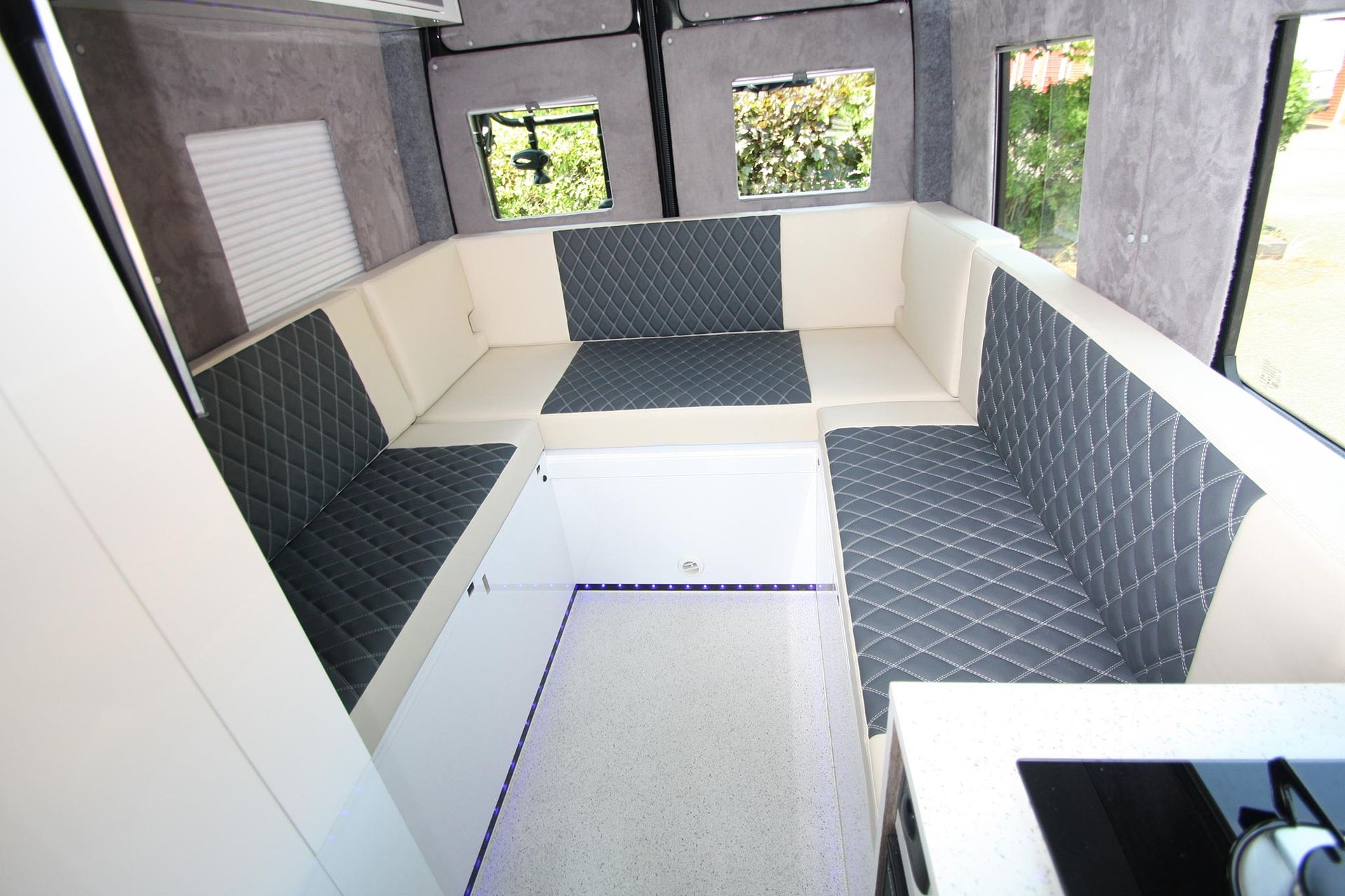 Small room with white benches and dark padded walls, viewed from an open doorway.