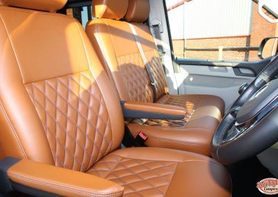 Tan leather car seats with diamond stitching and matching center armrest in a vehicle interior
