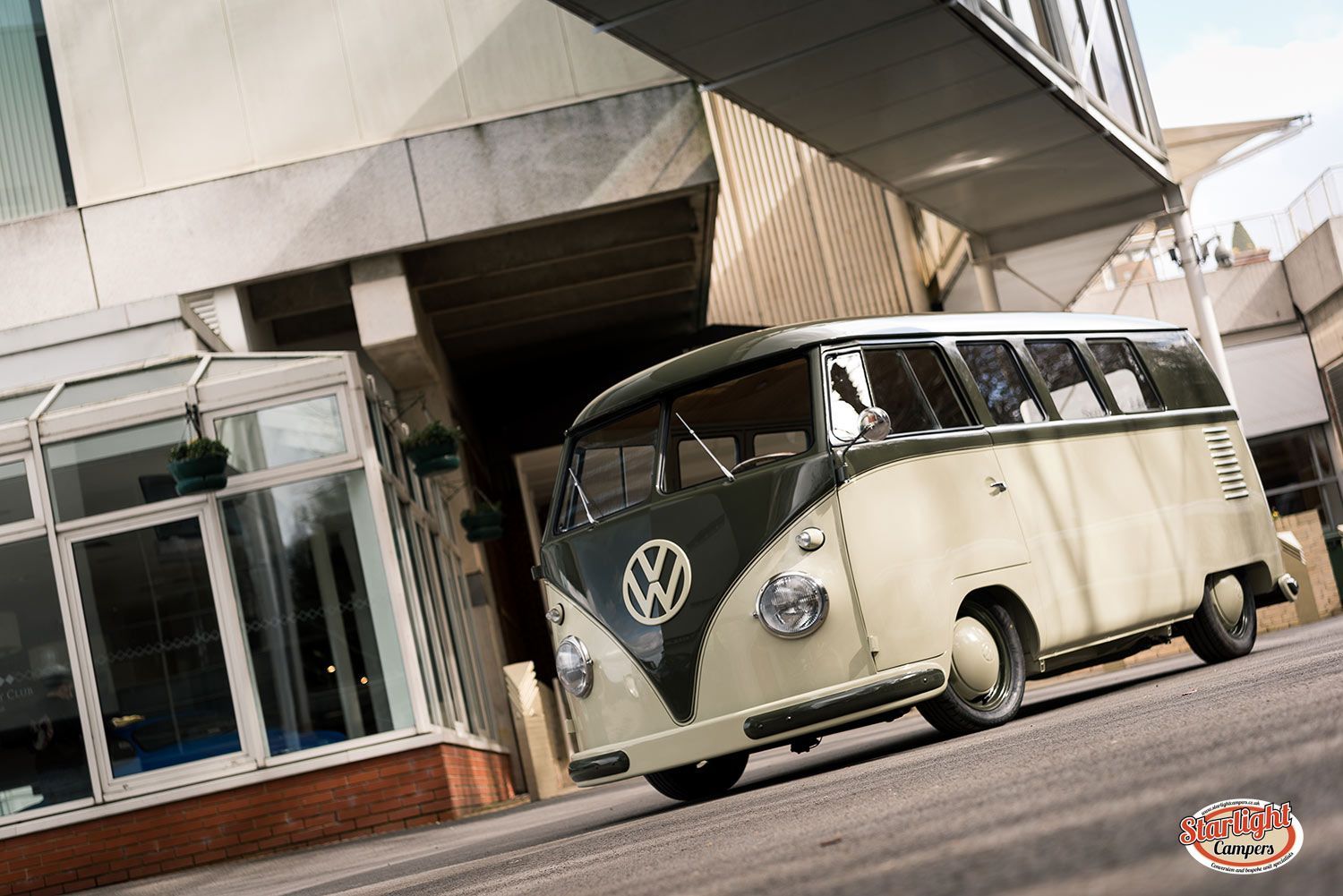 Vintage cream Volkswagen van parked by a modern building entrance.