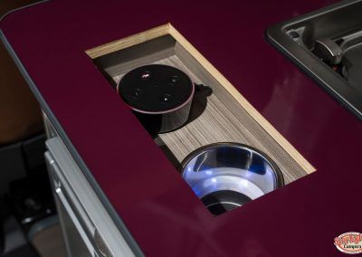 Wooden drink holder inset in a maroon vehicle console with two cup holders, one black and one chrome.