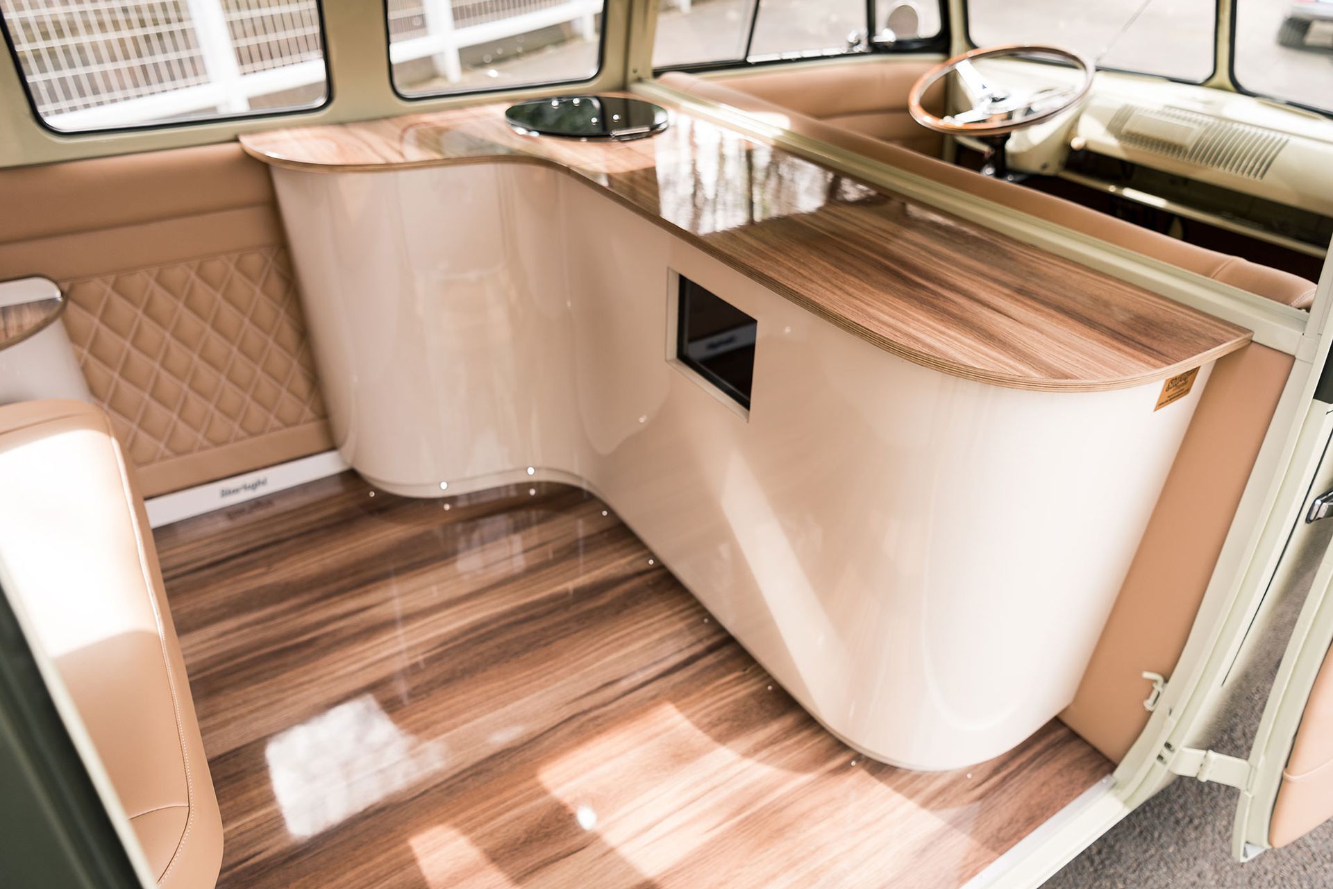 Compact beige cabin sink and countertop with wood flooring and quilted wall paneling in a small boat or RV interior