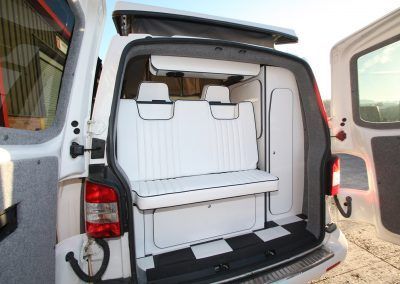 Van with a white foldable bench seat and storage area in the open rear cargo space