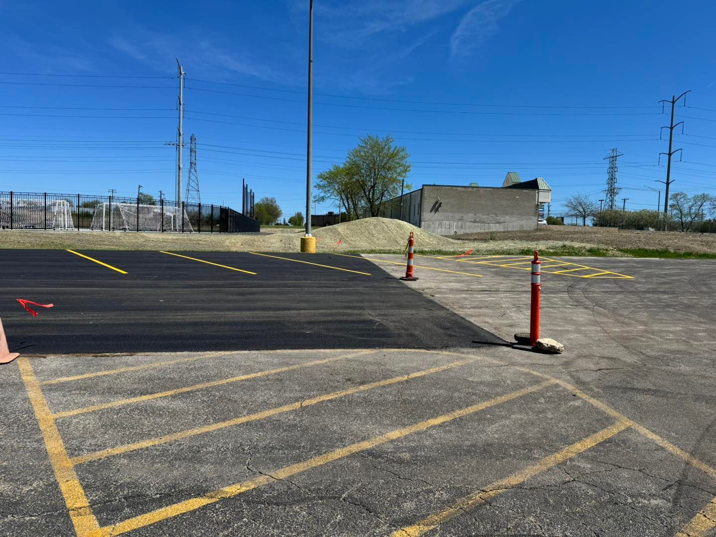 Empty parking lot with yellow lines, red cones, and a paved ramp under a blue sky