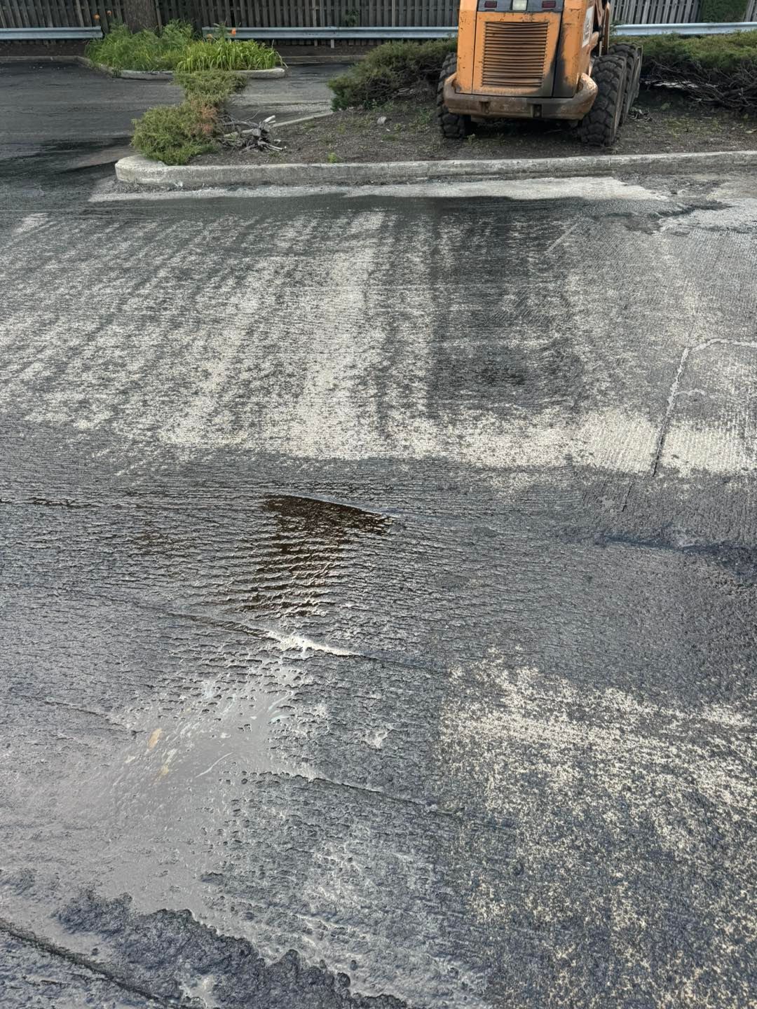 Damaged asphalt road with a small excavator parked at the top of the frame