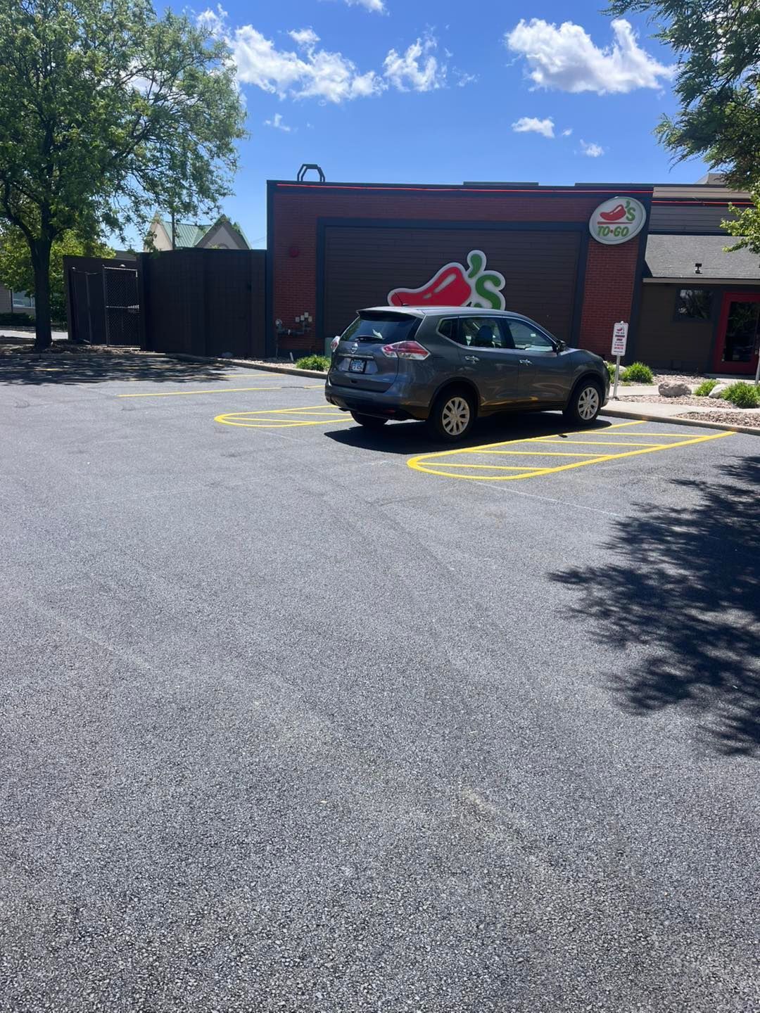 Black SUV parked outside a brick restaurant with a large red pepper sign on a sunny day
