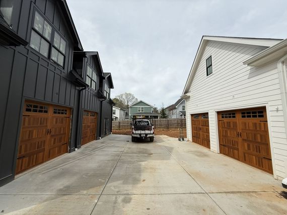 Two-story buildings with garage doors. A truck is parked between the structures on a concrete driveway.