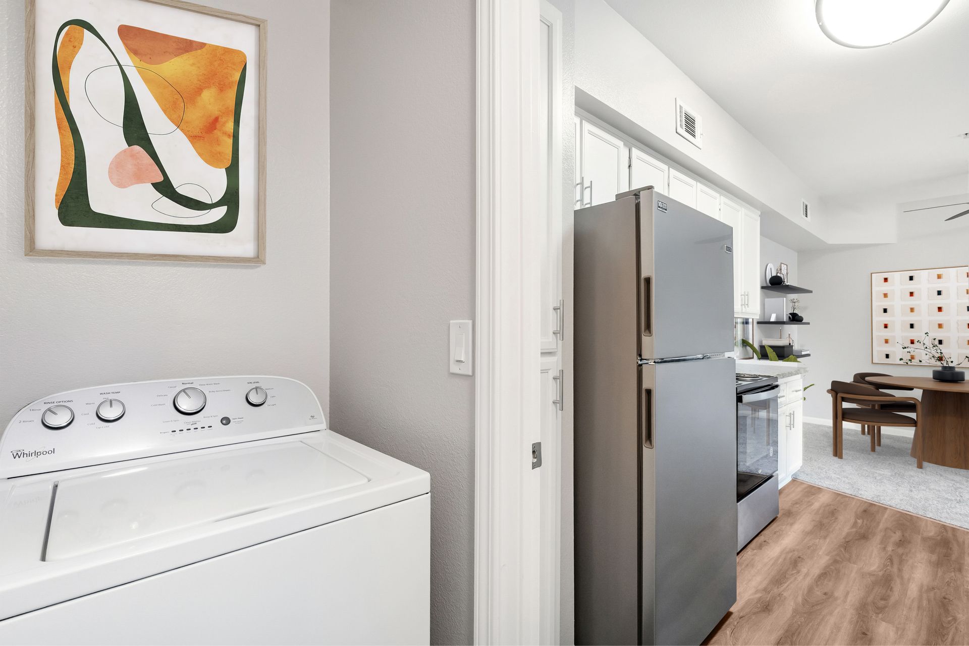 In-home washer and dryer adjacent to a modern kitchen with stainless steel appliances and an open-concept dining area.