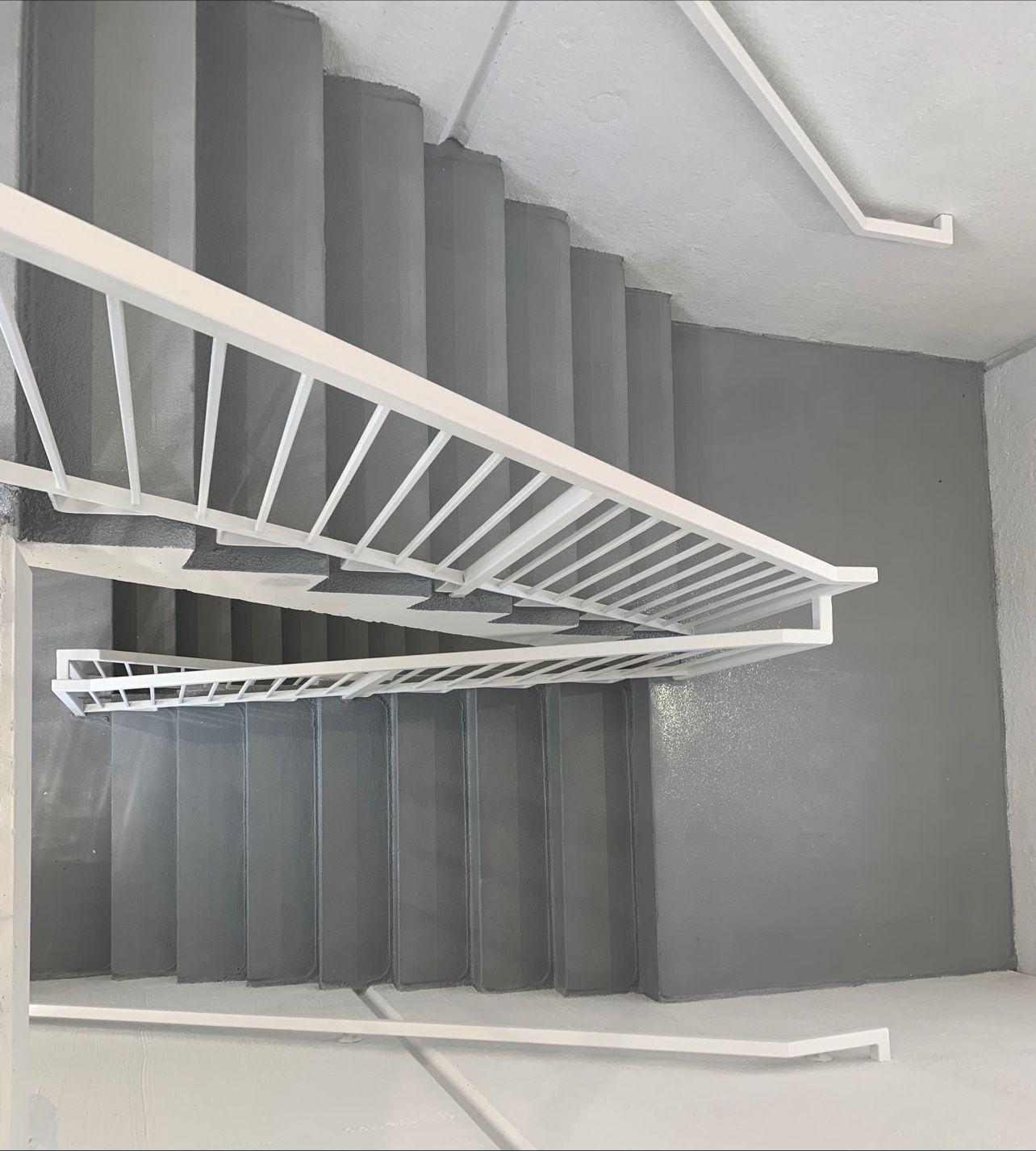 A staircase with a white railing and a gray wall.